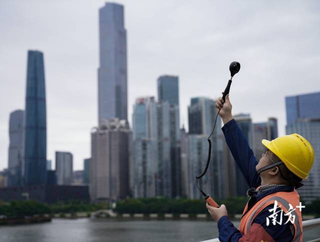 安全人员在珠江桥面测量风速，确保缆索上的同事在安全的环境下施工作业。
